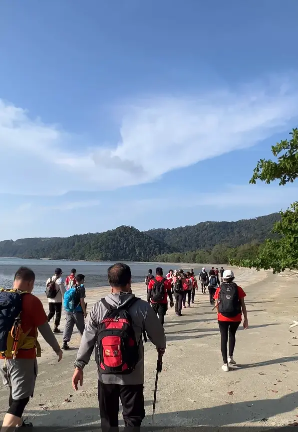 DAA Travel 爬山团队走在 Mersing 海边沙滩上